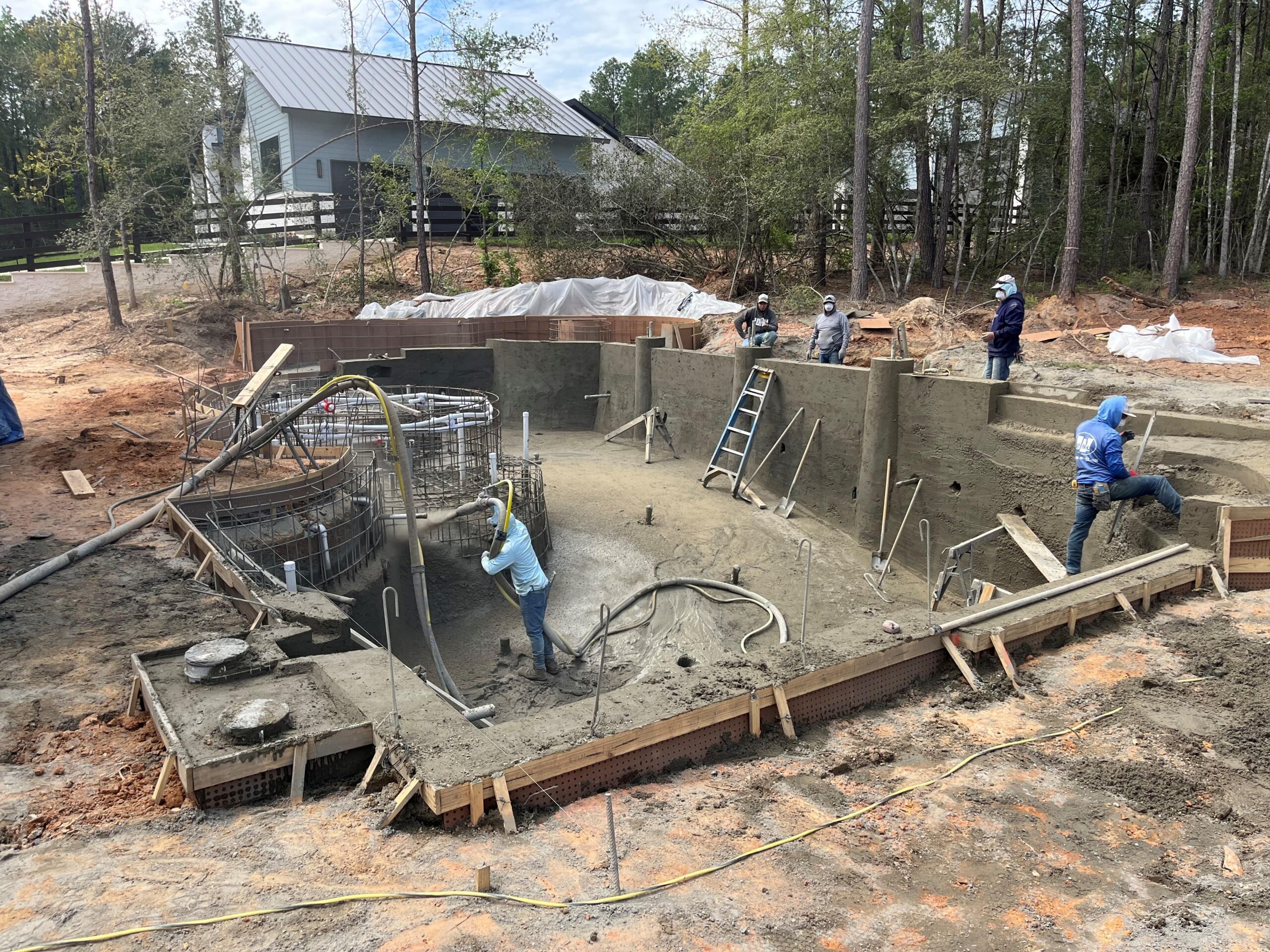 Gunite pool construction with blue water and backyard landscaping