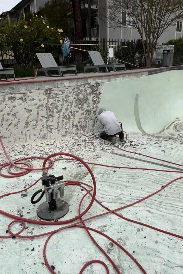Crew applying new pool plaster finish inside swimming pool